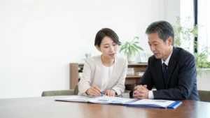 会議室で二人が机上の資料を確認する説明用イメージ