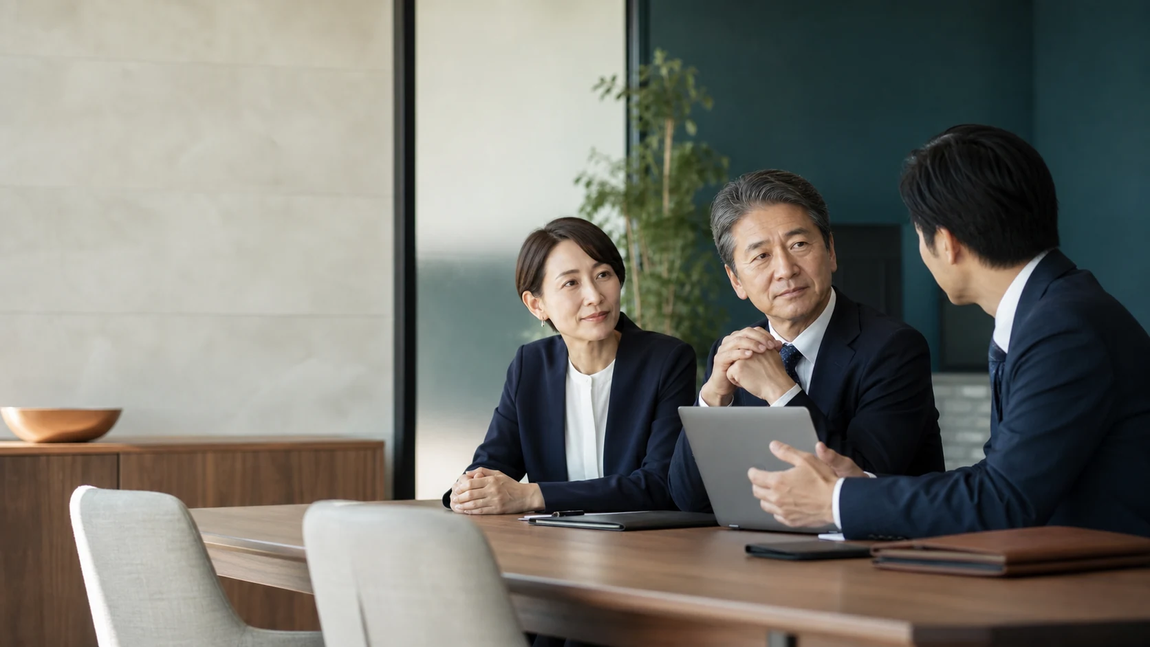 会議室で三人がタブレットを囲んで話すAI生成の説明用イメージ
